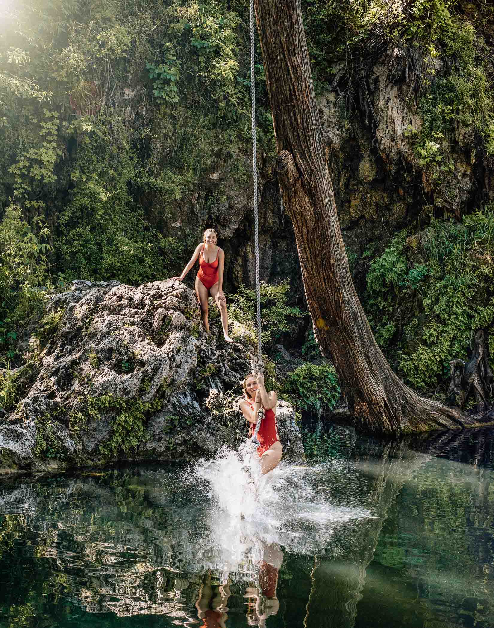 Young women enjoy a rope swing at Krause Springs water hole in TX
