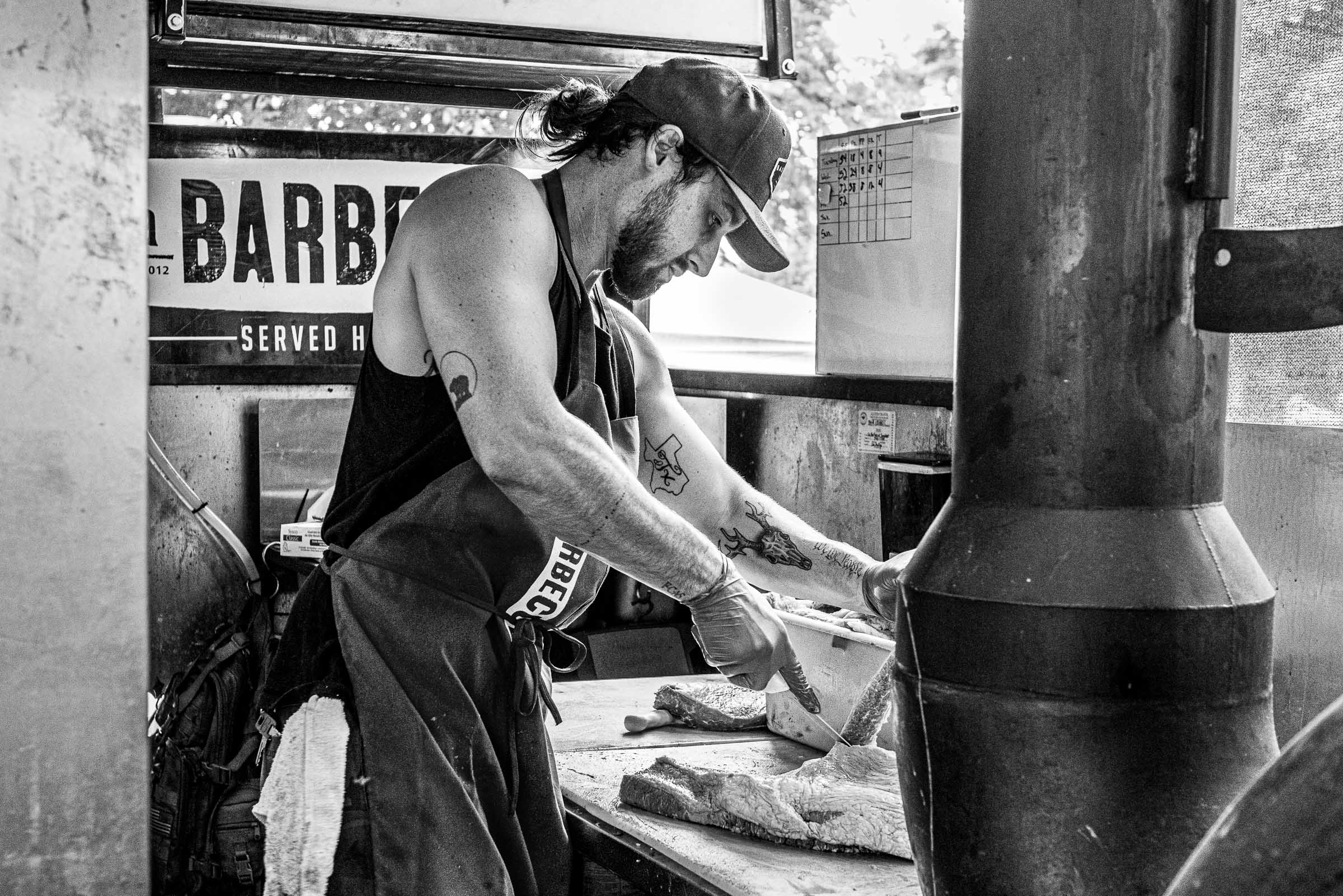 Black-and-white portrait of a butcher slicing meat at LaBarbecue-Texas-BBQ
