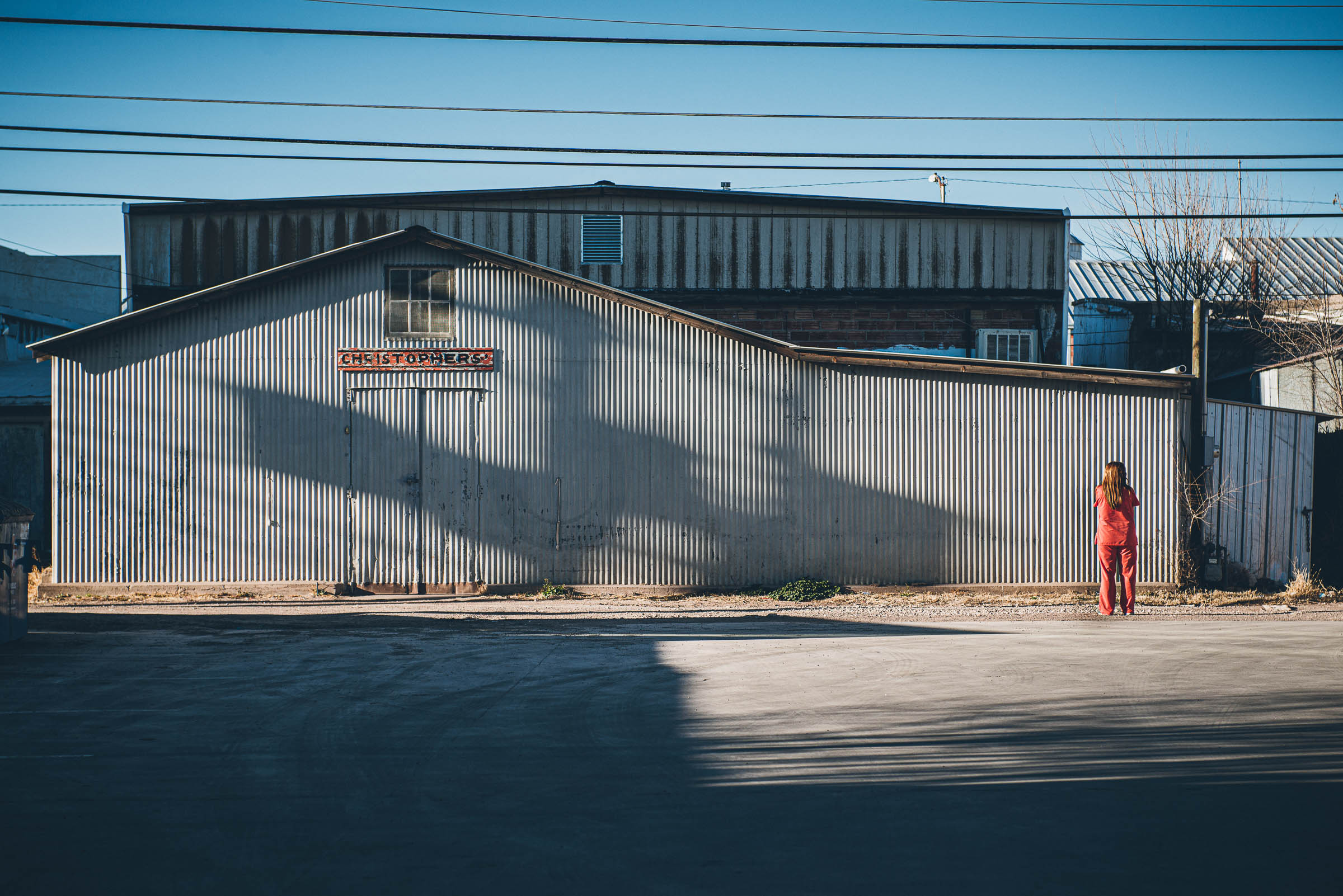 Lone woman in pink against industrial backdrop  -Marfa-Texas