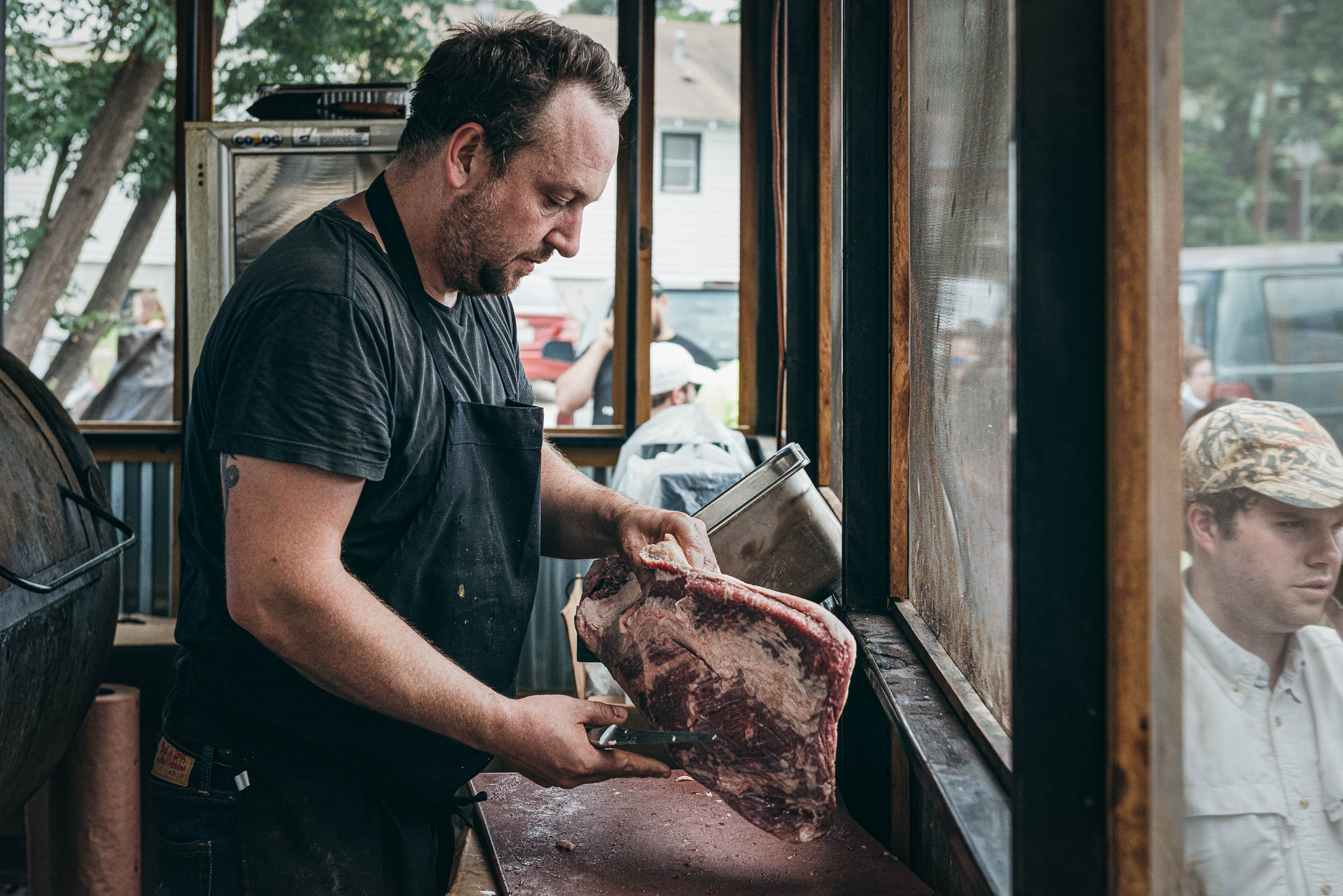 Tom Micklethwaite butchering meat at his BBQ trailer -in East Austin