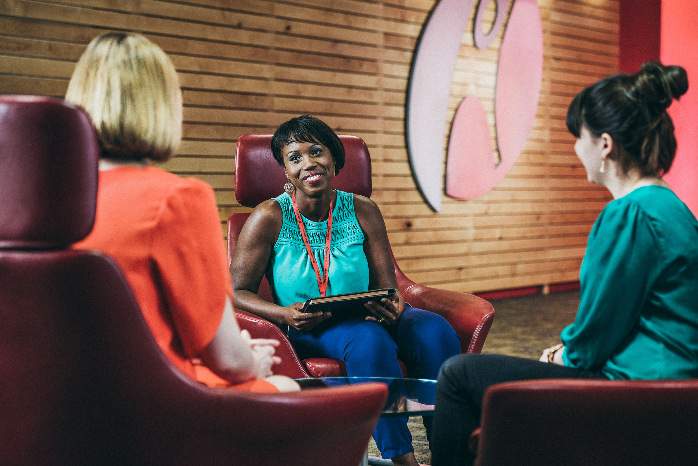 Business lifestyle photography -  three women talk in a colorful corporate environment.